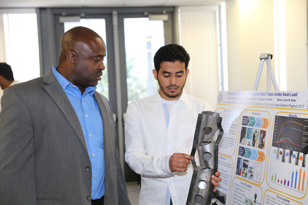 Abdullah Alotaibi explains his project involving the structural behavior of thin-walled steel tubes to Samueli School Dean Gregory Washington. 